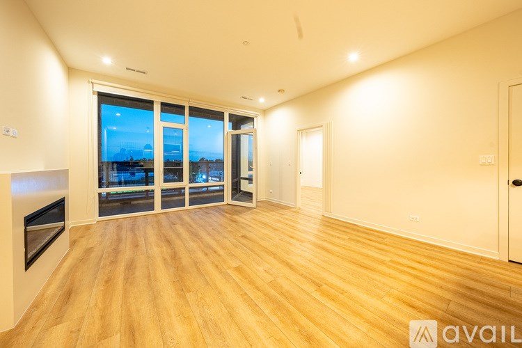 A spacious room with wooden flooring and a large window overlooking a cityscape.