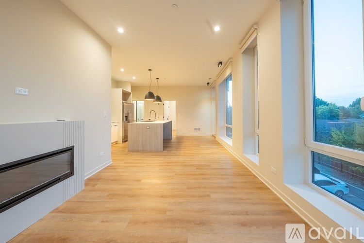 A spacious room with wooden floors and a large window on the right side.