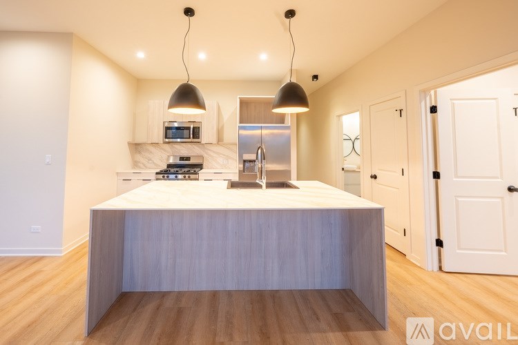 A modern kitchen with a central island and pendant lights.