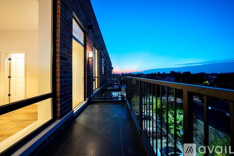 A balcony with a black railing and a view of the city at dusk.