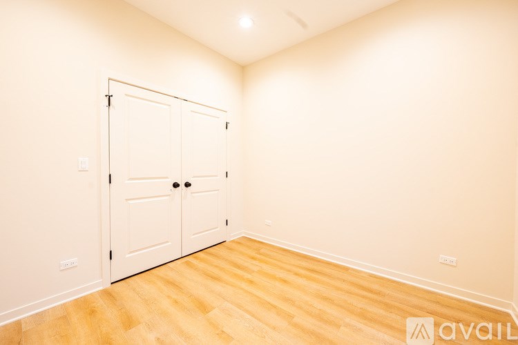 A room with a white door and wooden floor.