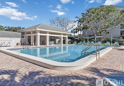 A pool area with a pavilion and a tree.