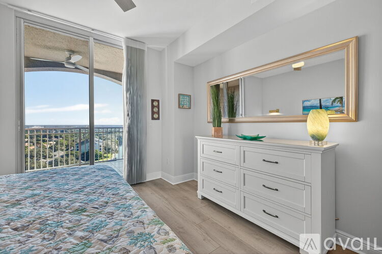 A bedroom with a dresser and a large window overlooking the ocean.