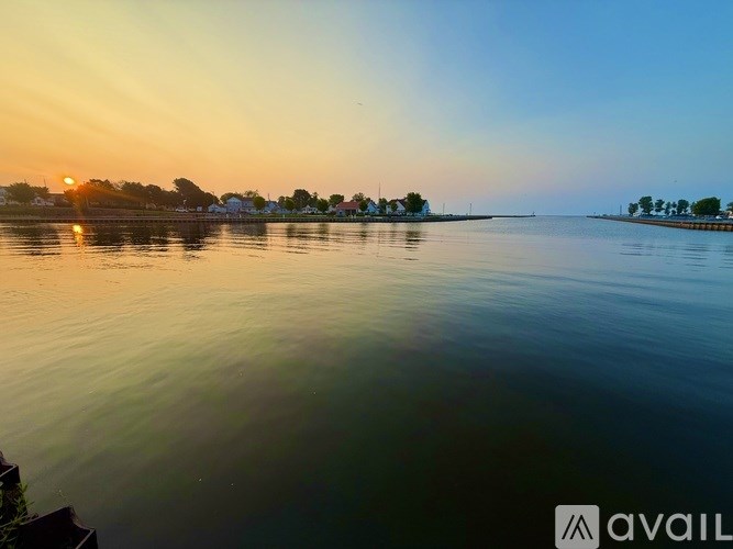 A sunset view over a calm body of water with buildings in the distance.