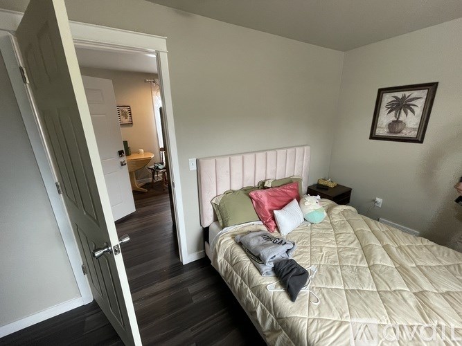 A bedroom with a bed, pillows, and a picture on the wall.