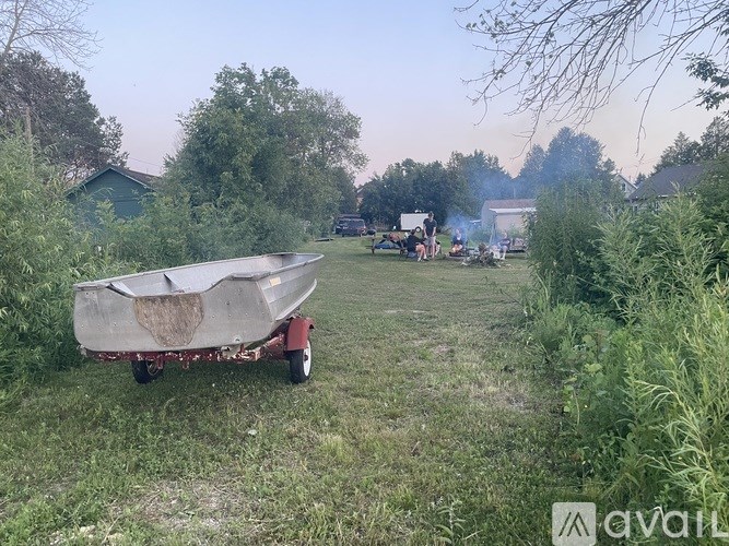 A boat is parked in a grassy area with people in the background.