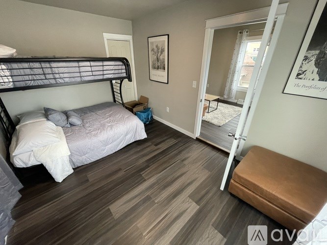 A bedroom with a bed, bench, and a painting on the wall.