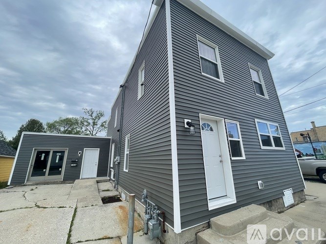 A grey house with a white door and windows is for sale.