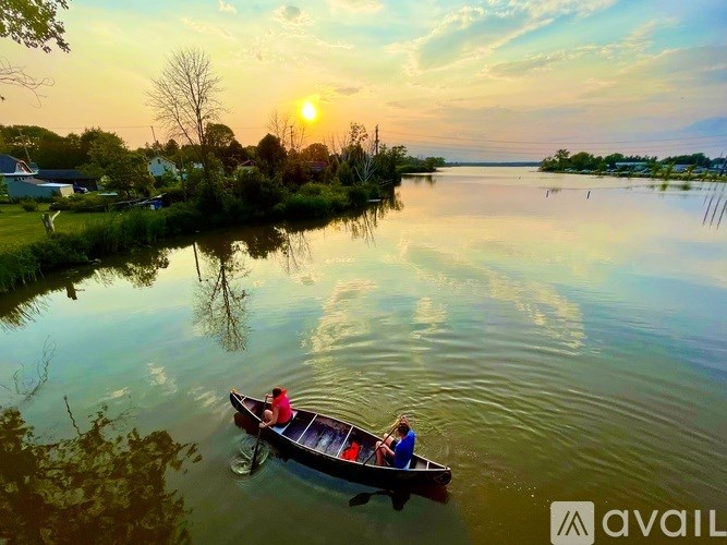 Two people in a boat on a calm lake during sunset.