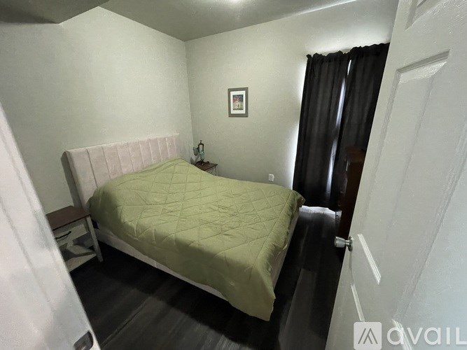 A bedroom with a bed, nightstand, and a picture on the wall.