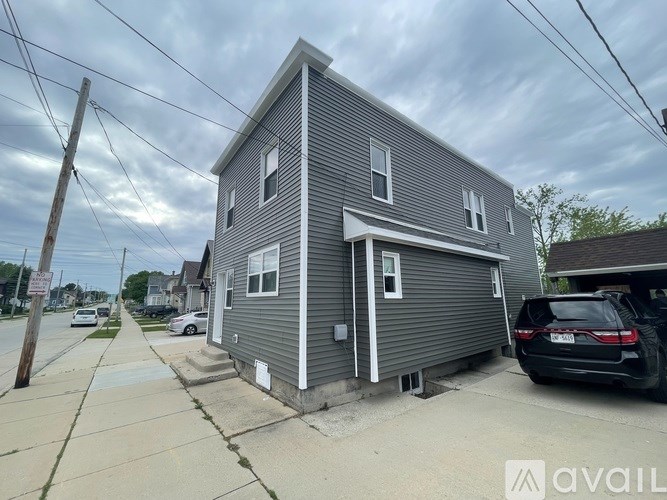 A grey house with a car parked in front.