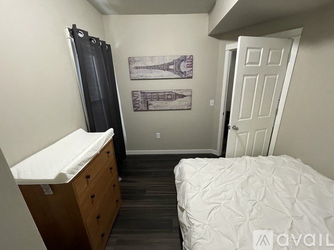 A bedroom with a bed, dresser, and two framed pictures on the wall.