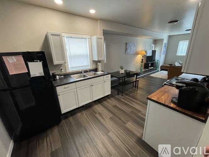 A kitchen with a black fridge, white cabinets, and a wooden countertop.