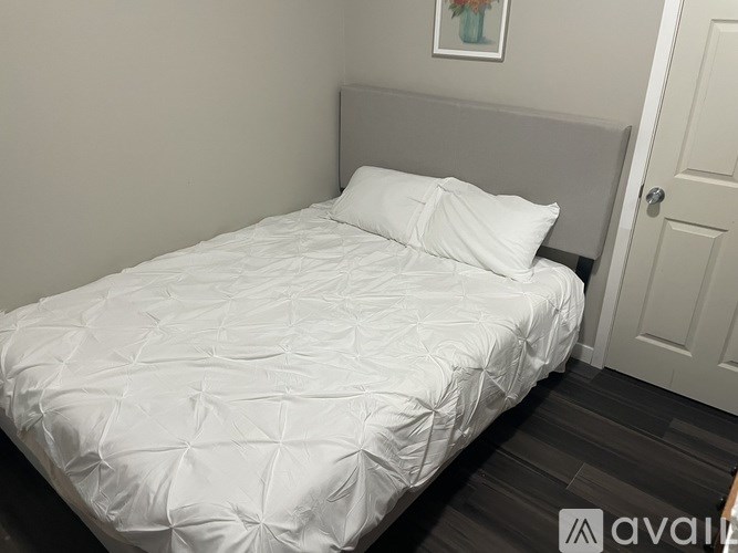 A white bed with a quilted cover and two pillows in a room.
