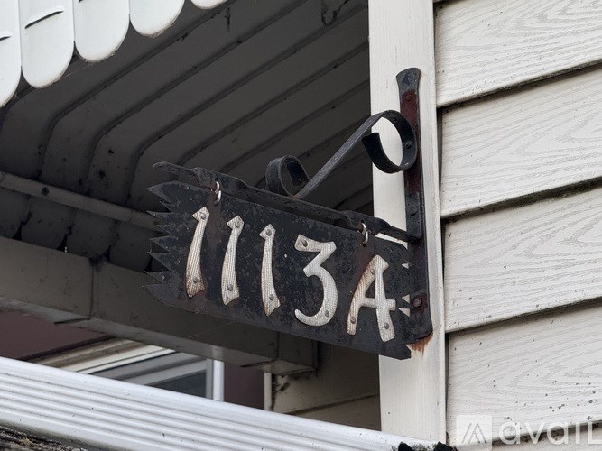 A black and white sign with the number 11134 is hanging from a metal bracket.