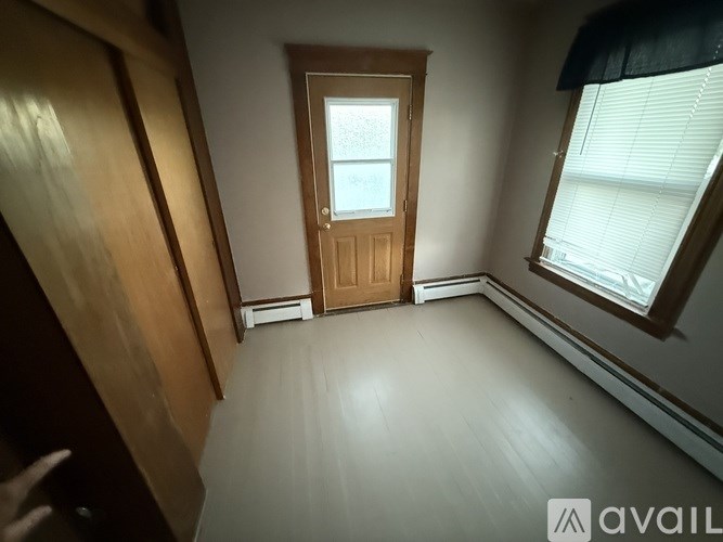 A room with a wooden door and a window with blinds.