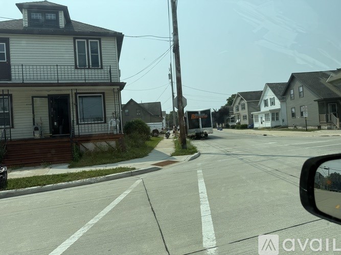 A street view with houses on both sides and a car parked on the side of the road.