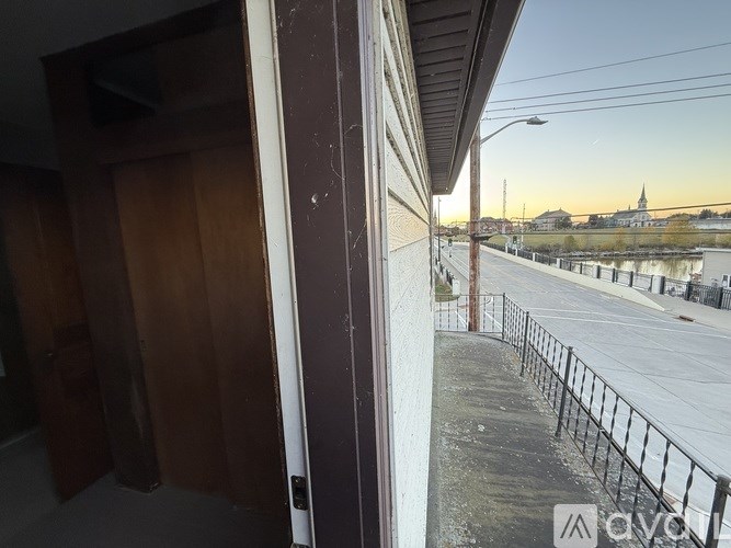 A street view with a sidewalk, a fence, and a sunset in the background.