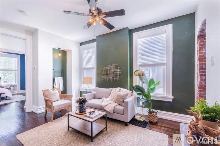 A living room with a white couch, a coffee table, and a ceiling fan.