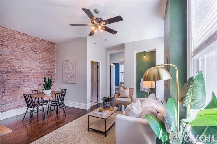 A living room with a brick wall and a ceiling fan.