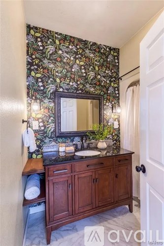 A bathroom with a floral wallpaper and a wooden vanity.