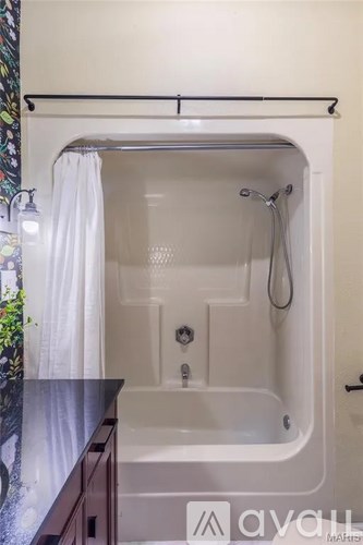A white bathtub with a shower head and a white curtain.