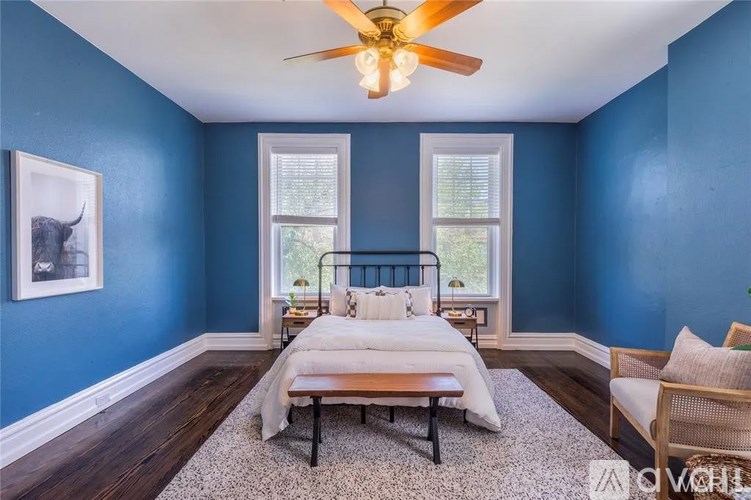 A bedroom with blue walls and a white bed.