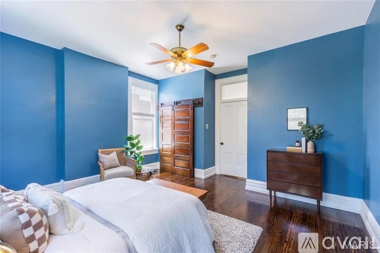 A bedroom with blue walls and a white bed.