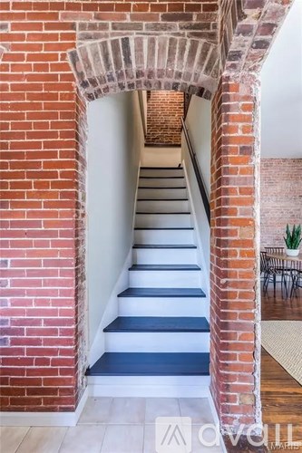 A staircase with a brick wall and a white railing.
