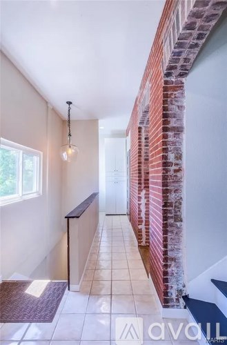 A hallway with a brick wall on the side and a tiled floor.