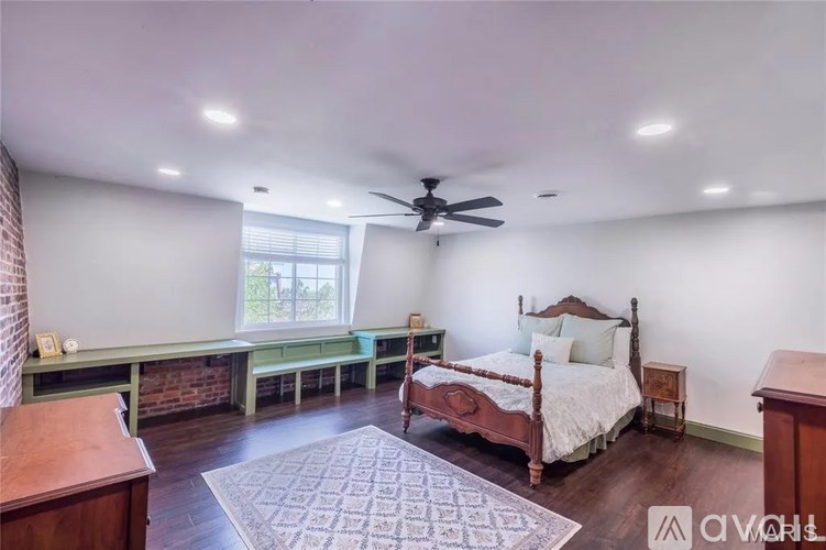 A bedroom with a bed, desk, and window.