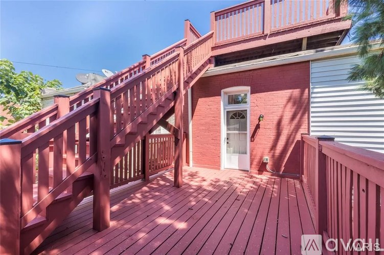 A red wooden deck with a staircase leading to a white door.