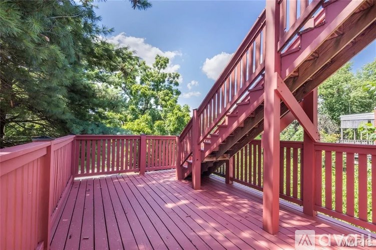 A wooden deck with a staircase leading to a balcony.