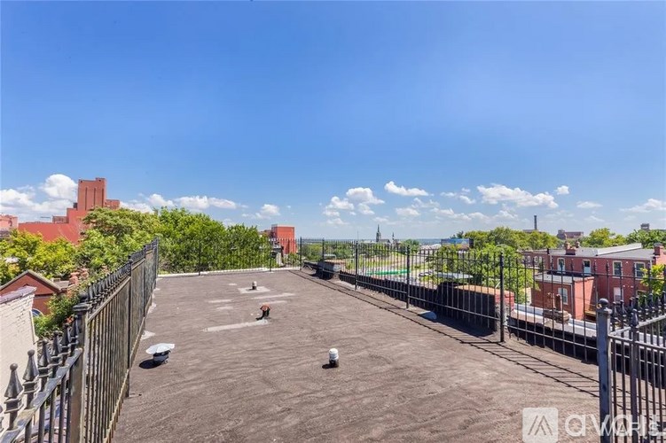 A rooftop with a fence and buildings in the background.