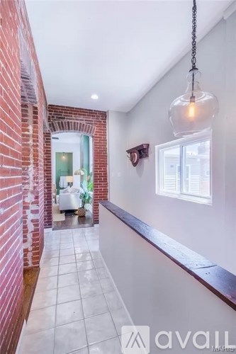 A hallway with a brick wall and a hanging light fixture.