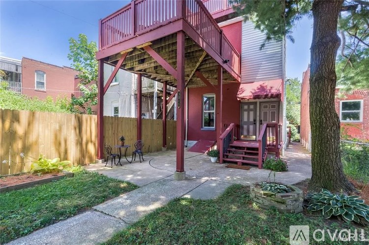 A red house with a balcony and a tree in front.