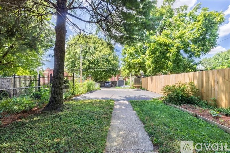 A tree-lined pathway leads to a house in the distance.