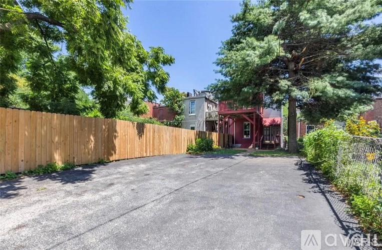 A driveway leads to a house with a red door.