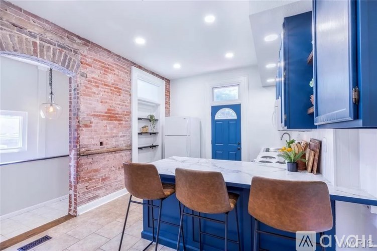 A kitchen with a brick wall and blue cabinets.