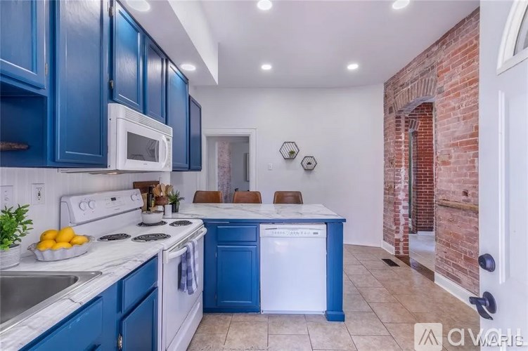 A kitchen with blue cabinets and white appliances.