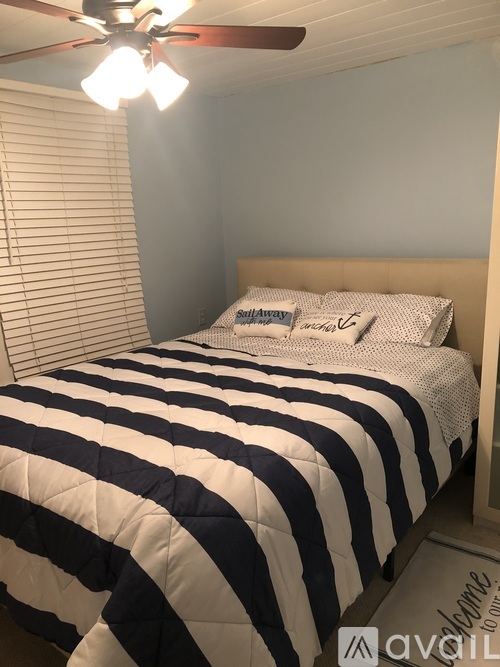A bed with a striped comforter and pillow with the word "Sleep" written on it.