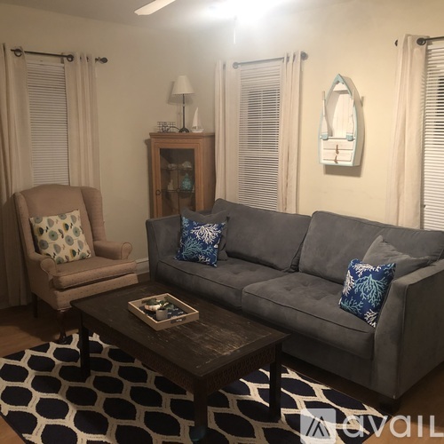 A living room with a grey couch, a brown armchair, and a coffee table with a book on it.