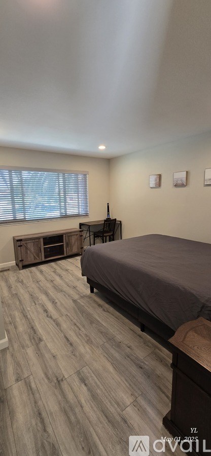 A bedroom with a bed, dresser, and window.