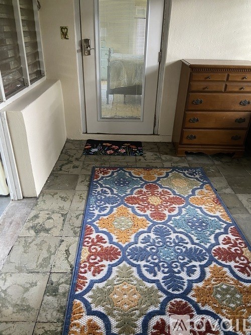 A room with a rug on the floor and a wooden dresser.