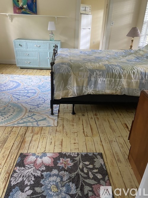 A bedroom with a bed, dresser, and rug.