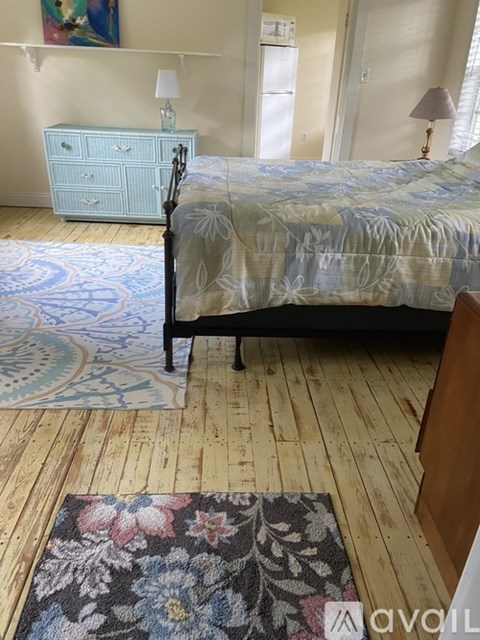 A bedroom with a bed, dresser, and rug.