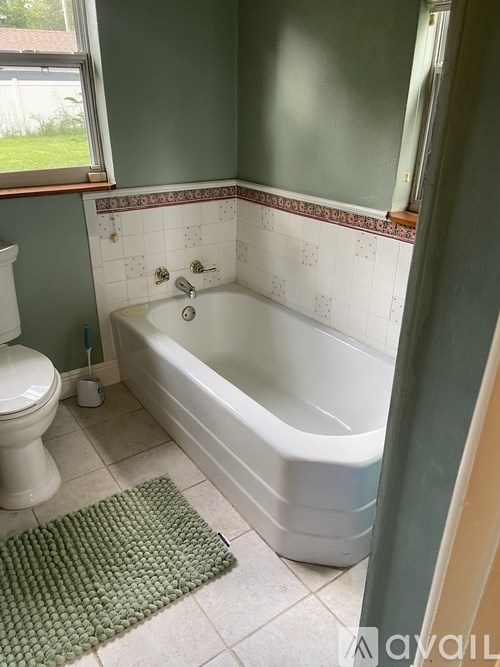A white toilet sits next to a bathtub in a bathroom.
