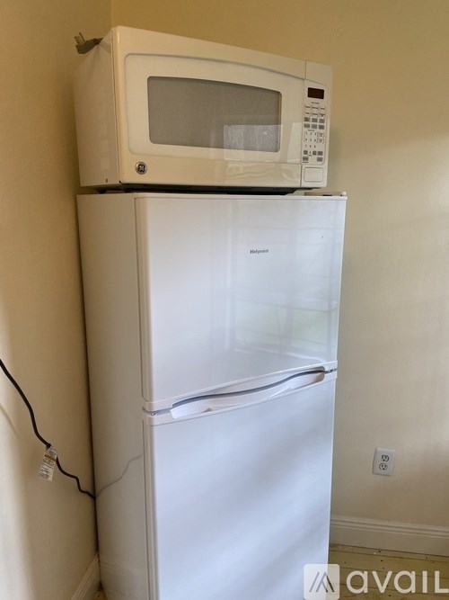 A white refrigerator with a microwave on top.