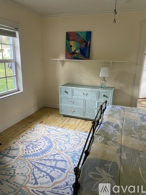 A bedroom with a bed, a dresser, and a painting on the wall.