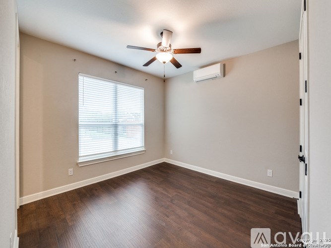 A room with a ceiling fan and a window with blinds.